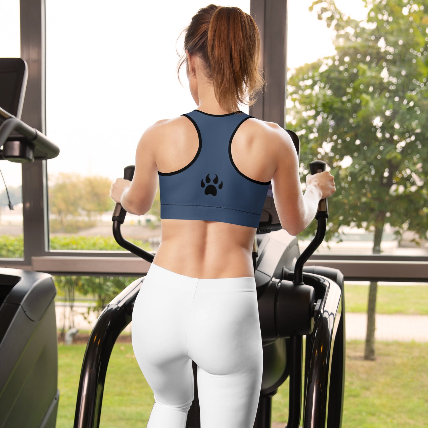 a woman on a treadmill wearing Sweetest Paw's Padded Sports Bra Stripe with a paw print on her leggings.
