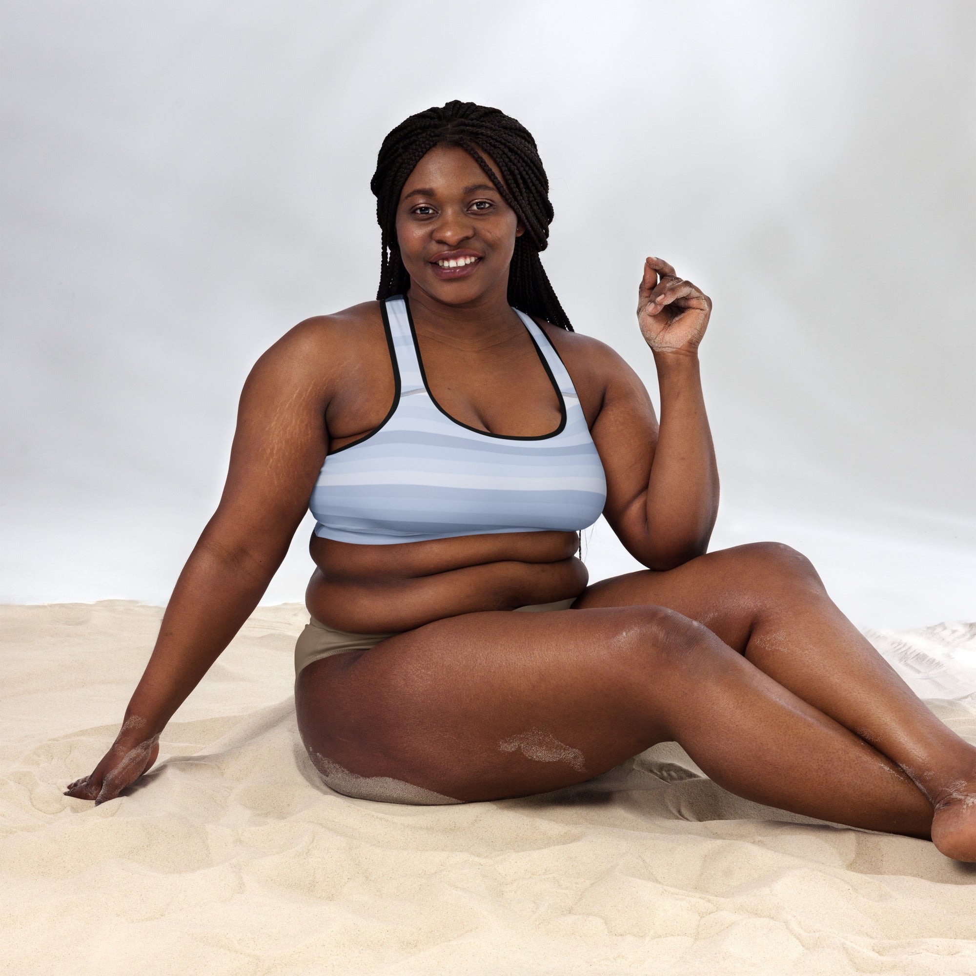 a black woman sitting on the sand in a Sweetest Paw Padded Sports Bra Stripe.