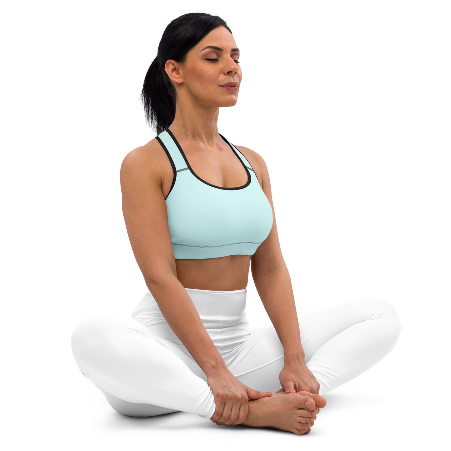 A woman is sitting in a yoga pose, wearing the Sweetest Paw Sports Bra Teal.